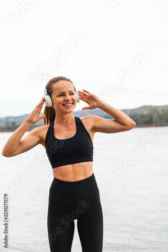 Portrait of a positive fit woman in wireless headphones outdoors.
