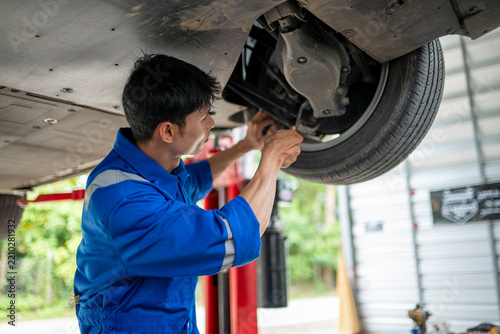 Asian mechanic performing car inspection and maintenance