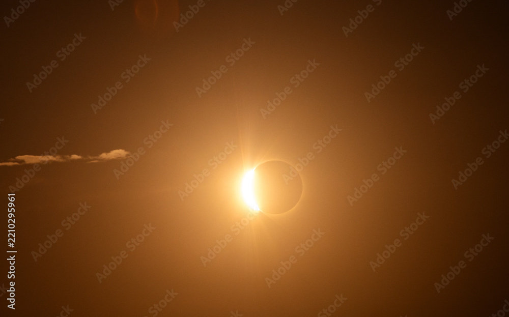 Fototapeta premium Partial Solar Eclipse Shining Through a Golden Hazy Sky