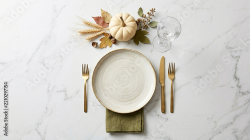 Thanksgiving place setting with pumpkin and autumn leaves on marble