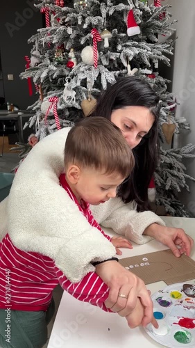 Mother and son painting white dots on cardboard