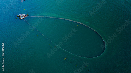 Aerial view of a large circular fishing net deployed by local fishermen in the calm waters of Kaptai Lake in Rangamati, Chittagong Division, Bangladesh.