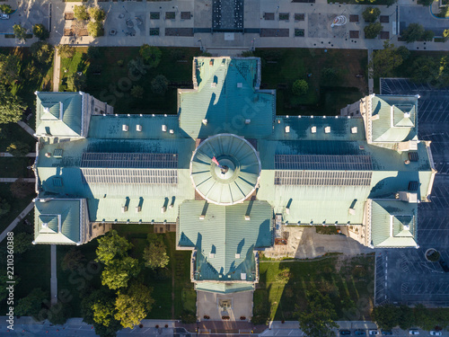 Aerial view of the Indiana Statehouse with its distinctive green copper dome, symmetrical wings, and surrounding park grounds in Indianapolis, Indiana, United States.