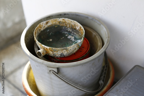Old rusty kitchenware stored in plastic bucket.