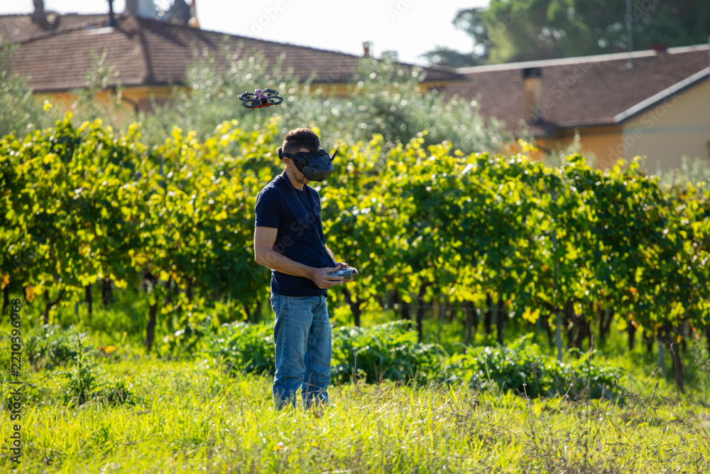 Fototapeta premium Man flying FPV racing drone in vineyard