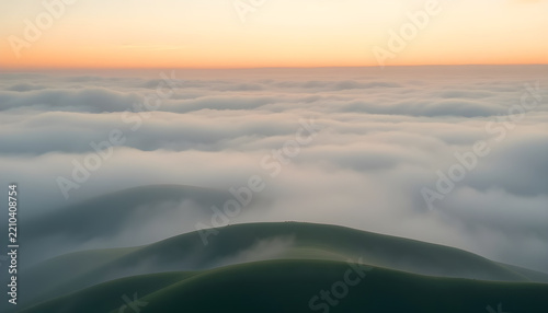 Foggy landscape with layered green hills at sunrise