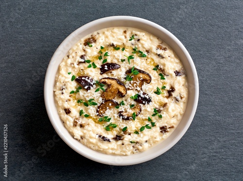 creamy mushroom risotto in circular white bowl against slate grey background