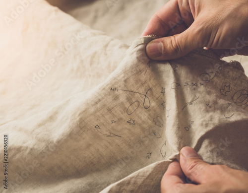 Hand drawn doodle scribble on crumpled linen fabric with visible hand creating textile texture and creative ambiguity