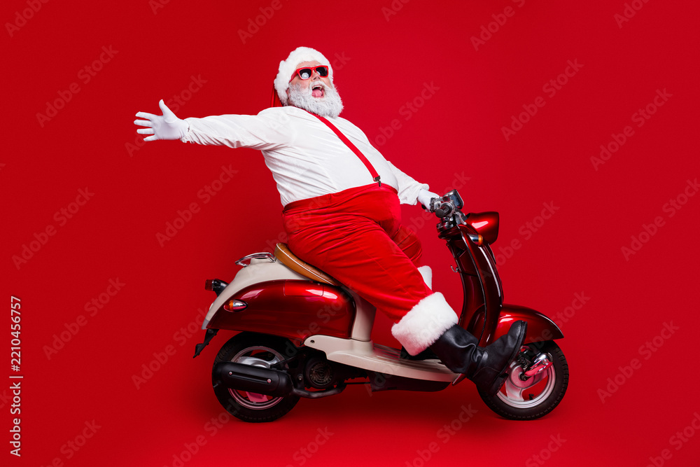Obraz premium Santa Claus on a red scooter celebrating Christmas with joy and festive style against a bold red background