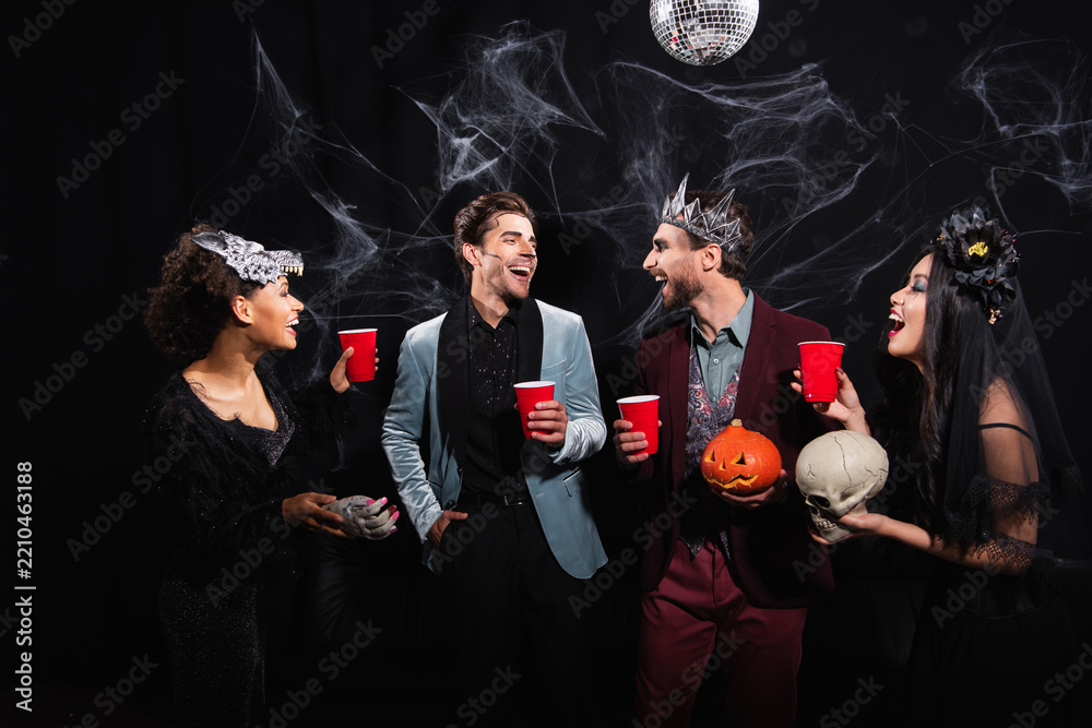 Obraz premium Friends celebrating Halloween with joyful costumes and drinks at a lively party