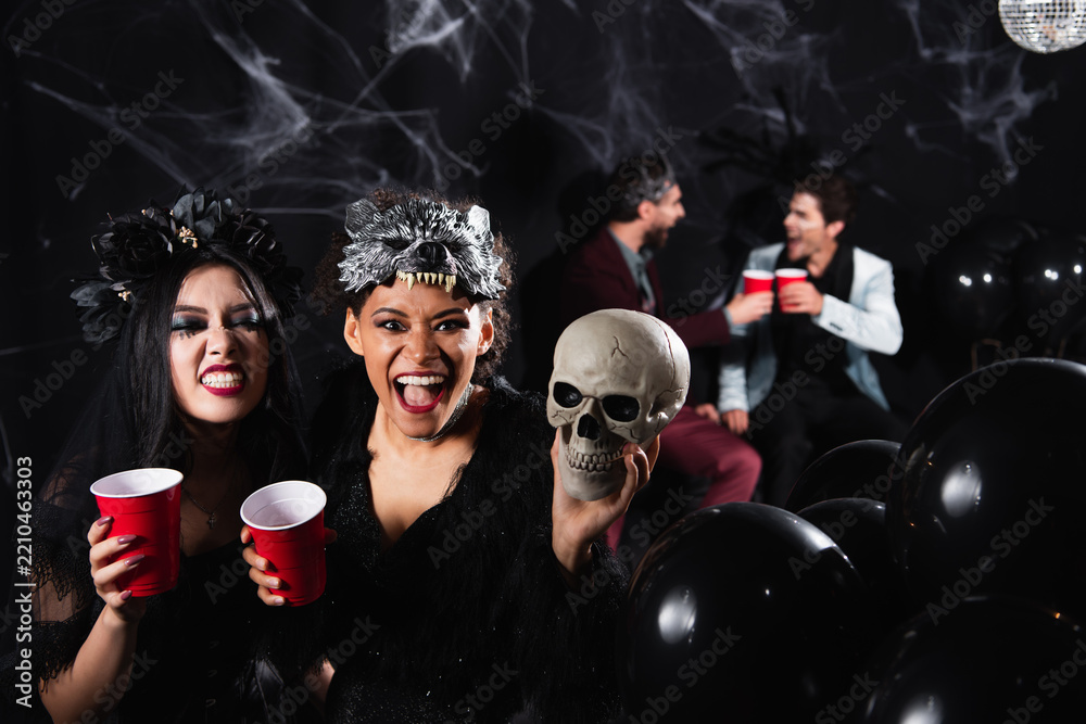 Obraz premium Multicultural female friends celebrate Halloween at a fun costume party