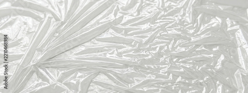 Close-up of crumpled white plastic material, creating an abstract, textured background. Ideal for various design projects, including banners and posters.