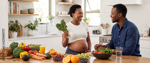Pregnant woman and partner enjoying healthy food in modern kitchen, maternity nutrition, balanced diet, fresh vegetables, prenatal wellness, expecting baby