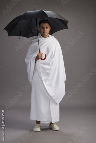 Clean-Shaven Man in Ihram Attire Holding an Umbrella