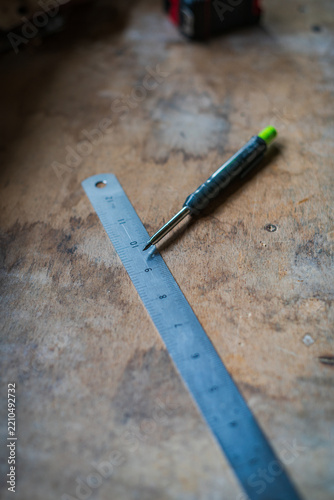 View of a metal ruler and a mechanical pencil resting on a weathered wooden workbench in Looe, Cornwall, United Kingdom.