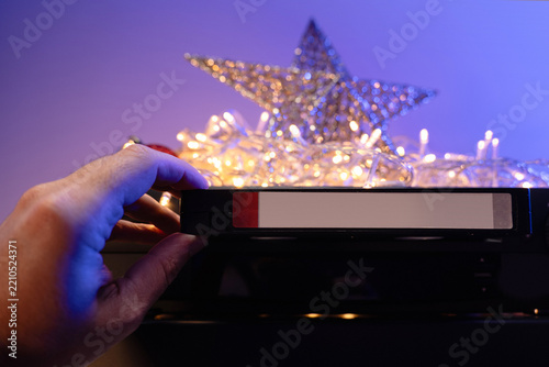  Christmas movie night with VHS tape, vintage VCR and CRT television surrounded by glowing festive lights.