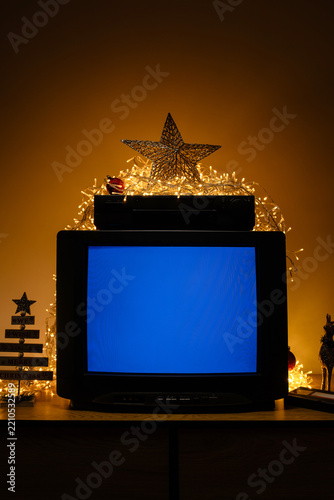 Retro CRT television with VCR and Christmas lights, blue no signal screen in festive holiday interior