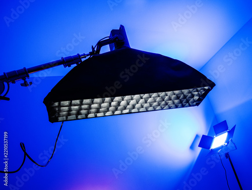 Professional studio lighting setup with large softbox and LED panel under blue ambient light
