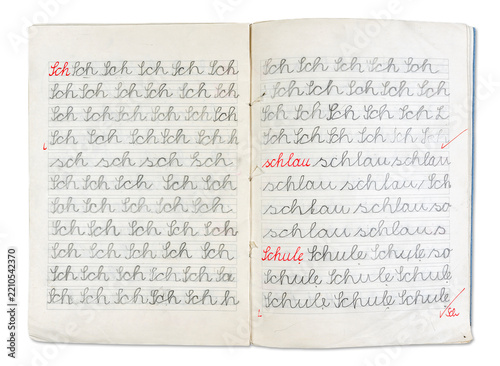 Open handwriting practice notebook, pages filled with cursive script. Primary exercise book with written words and letters for learning first alphabet writing. Book isolated on white background.