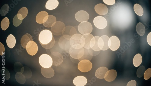 Abstract background with soft golden bokeh circles glowing against a dark and moody blurred backdrop