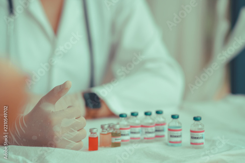 Gloved hand gesturing beside a row of labelled vials