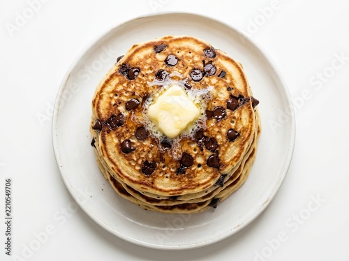 Delicious Stack of Homemade Chocolate Chip Pancakes with Melting Butter and Syrup on a White Plate, Top View