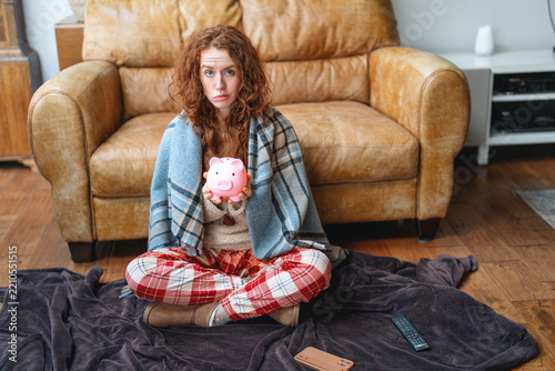 Person sitting on a blanket holding a piggy bank in a living room