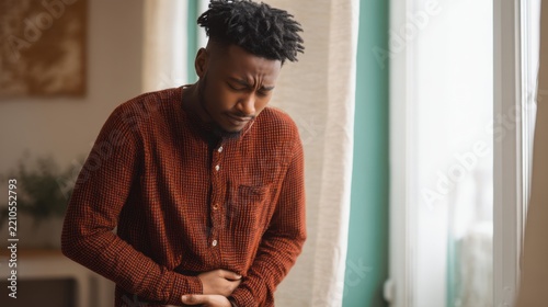 Young African American Man Suffering from Severe Stomach Pain and Abdominal Cramps at Home