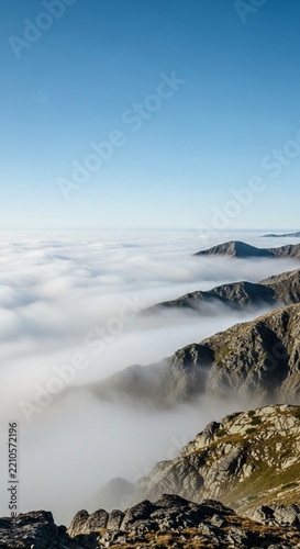 Thick White Fog Rolling Beneath a Bright Blue Sky Over Mountain Peaks