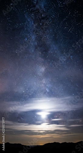 Thin wispy clouds illuminated by the light of many bright stars in the night sky