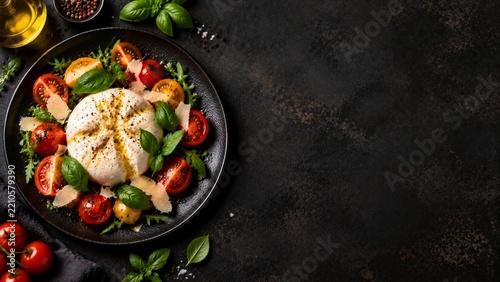 Fresh Burrata Cheese With Tomatoes and Basil on a Black Plate