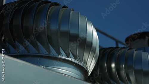 Rotating metal rooftop turbine ventilators against blue sky
