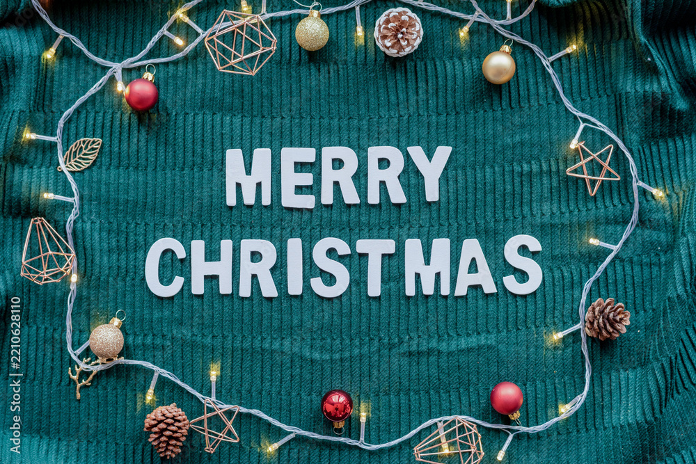 Obraz premium Merry Christmas greeting on green knit background with festive decor