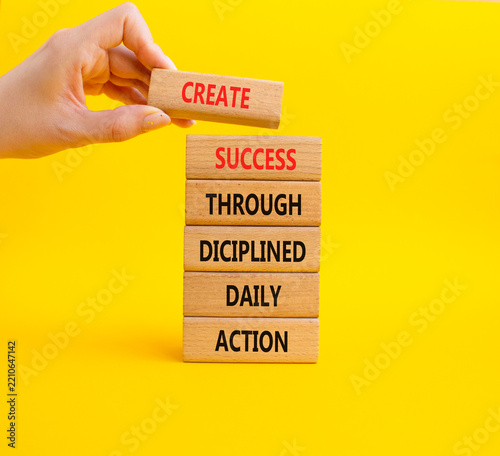 Concept words create success through disciplined daily action on wooden blocks. Businessman hand. Beautiful yellow background. Business concept. Copy space.