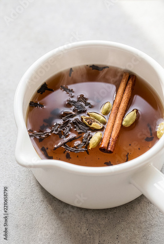 Hot spiced chai tea brewing with cinnamon sticks cardamom and black tea leaves
