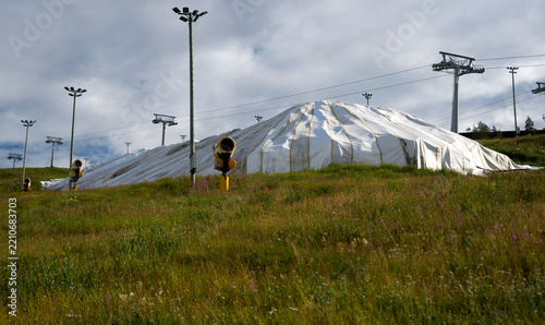 Artificial snow farming, snow cannon on ski slope in Arctic summer