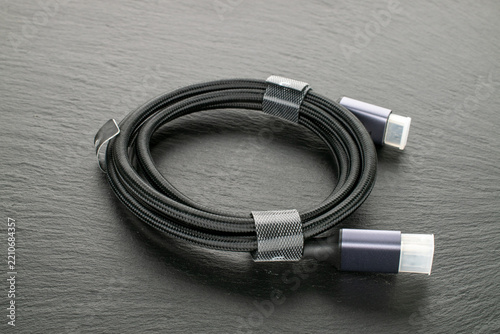 High-speed HDMI cable with nylon braiding and protective caps on slate stone, macro shot.