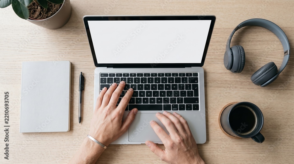 Fototapeta premium Hands type on a laptop with blank white screen beside headphones, coffee and notebook. Concept remote work and digital productivity for advertising, websites and blogs. Generative AI.