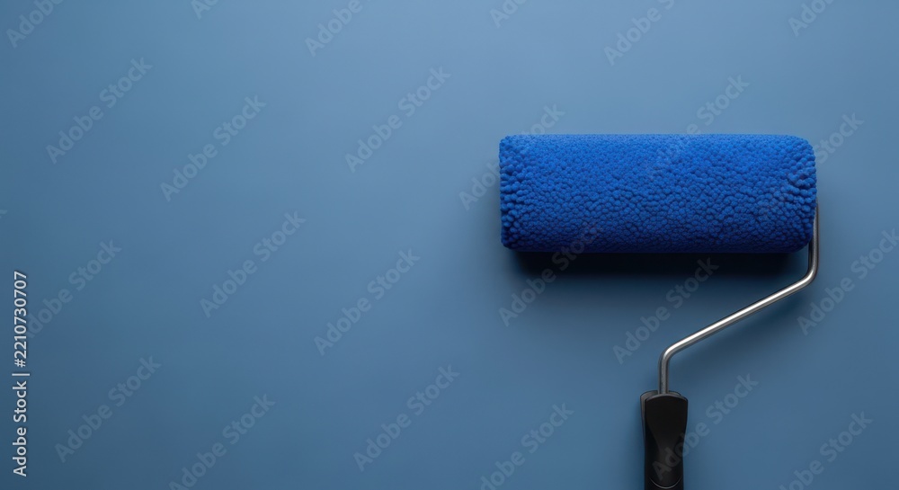 Obraz premium Blue paint roller with a textured foam head against a solid matte blue wall background surface