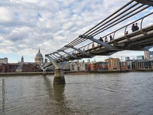 Millennium Bridge and St Paul's Cathedra - A view of the Millennium Bridge pedestrian crossing the River Thames in London with St Paul's Cathedral and city buildings in the background