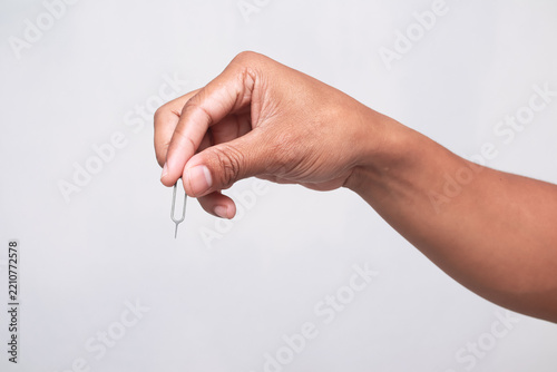 Man holding a sim card ejector tool between fingers isolated on white background