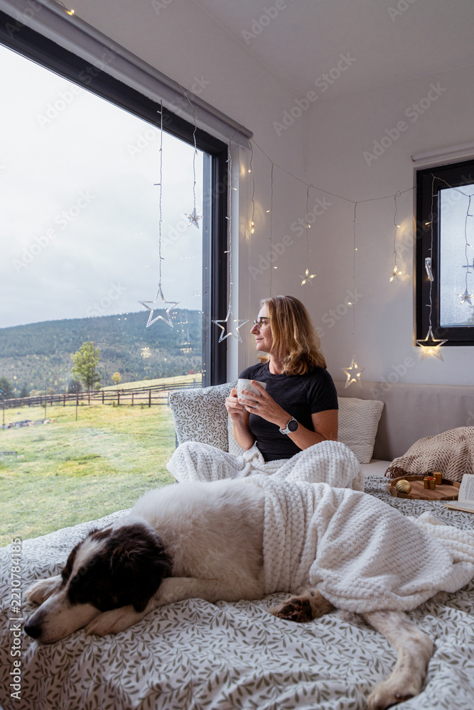 Obraz premium happy woman with dog relaxing in bed at Christmas time
