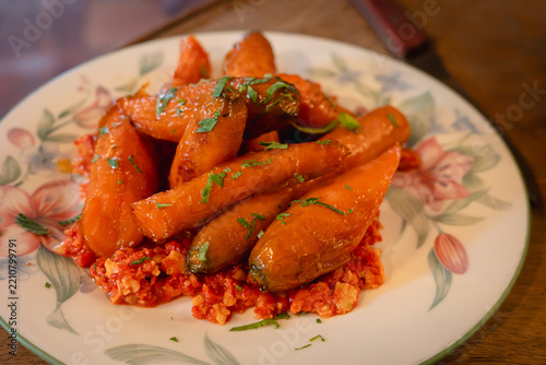 Honey roasted organic carrots served with a romesco sauce on a plate with a flower pattern.