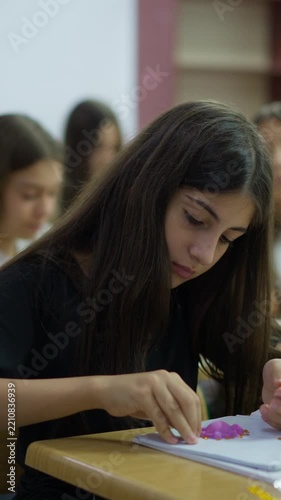 A young student focuses on a creative craft project using modeling clay at a classroom desk