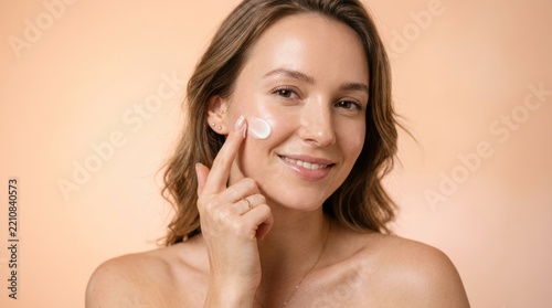 Beautiful young woman with clean, perfect skin. Portrait of a beauty model with natural nude makeup touching her face. Spa, skincare, and wellness. Close-up, copy space. 