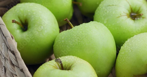 Bright and juicy green summer apples in a wicker basket. Cultivation of apples and apple farming. Home apple orchard.