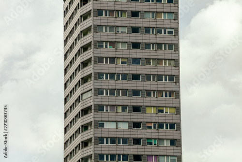 Tall residential building with colorful windows against cloudy sky