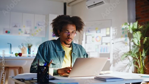 Young programmer typing laptop drinking coffee. Developer working loft office.