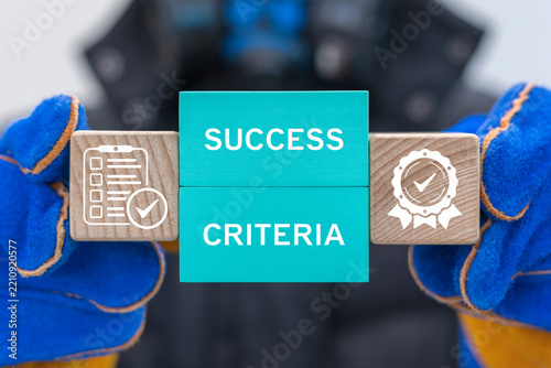 Worker holding blocks with icons sees the text SUCCESS CRITERIA. Concept of industry success criteria. Manufacturing criteria standards evaluation.
