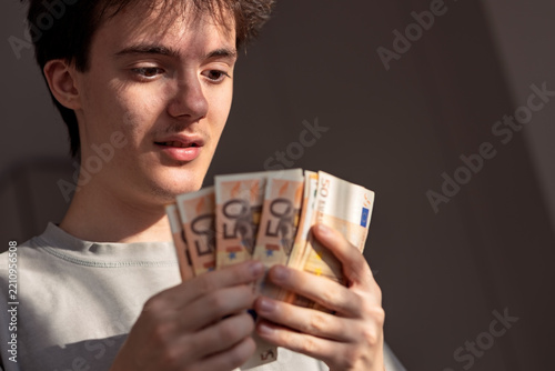 Young person looking closely at euro banknotes in his hands